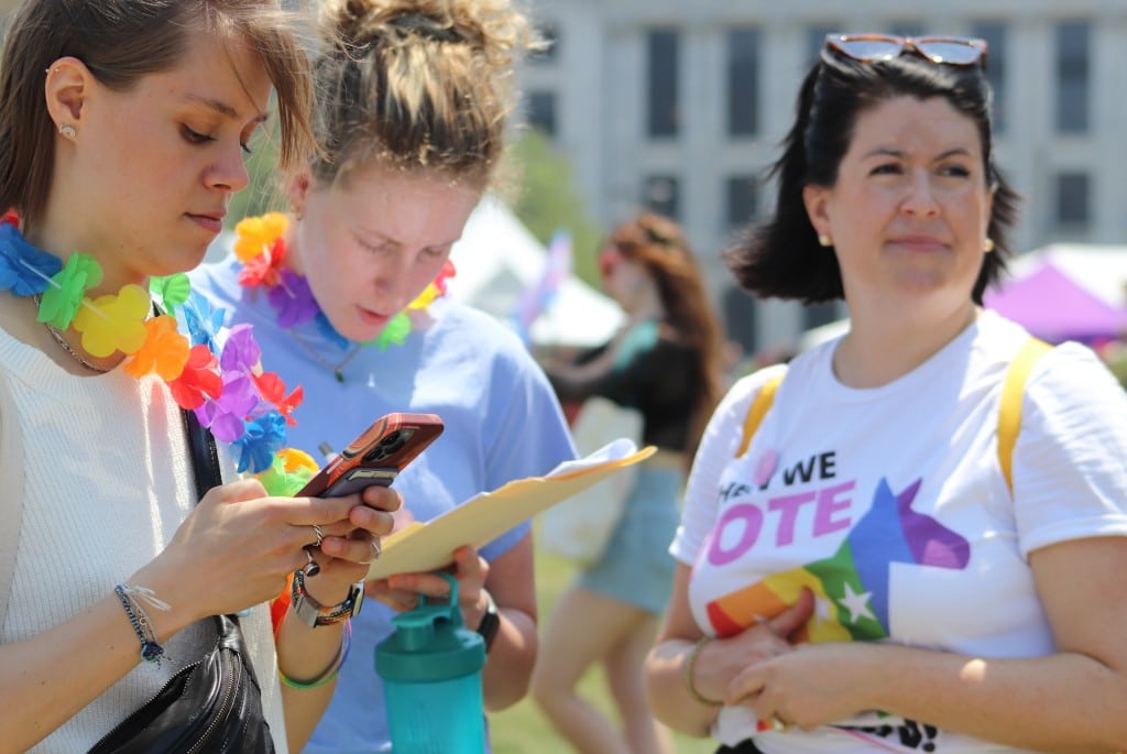 Someone checks their phone while others wear a "Today we VOTE" shirt.