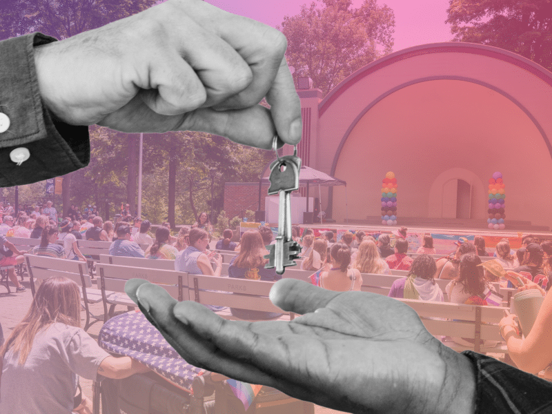 Two people exchange keys in front of a rainbow gradient backdrop of Findlay's Pride in the Park.