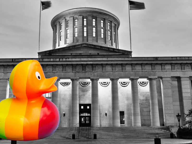 A rainbow duck is in front of the Ohio Statehouse in black-and-white.