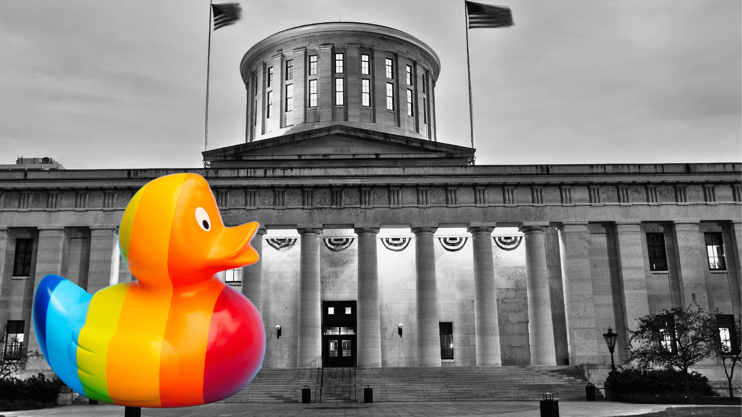 A rainbow duck is in front of the Ohio Statehouse in black-and-white.