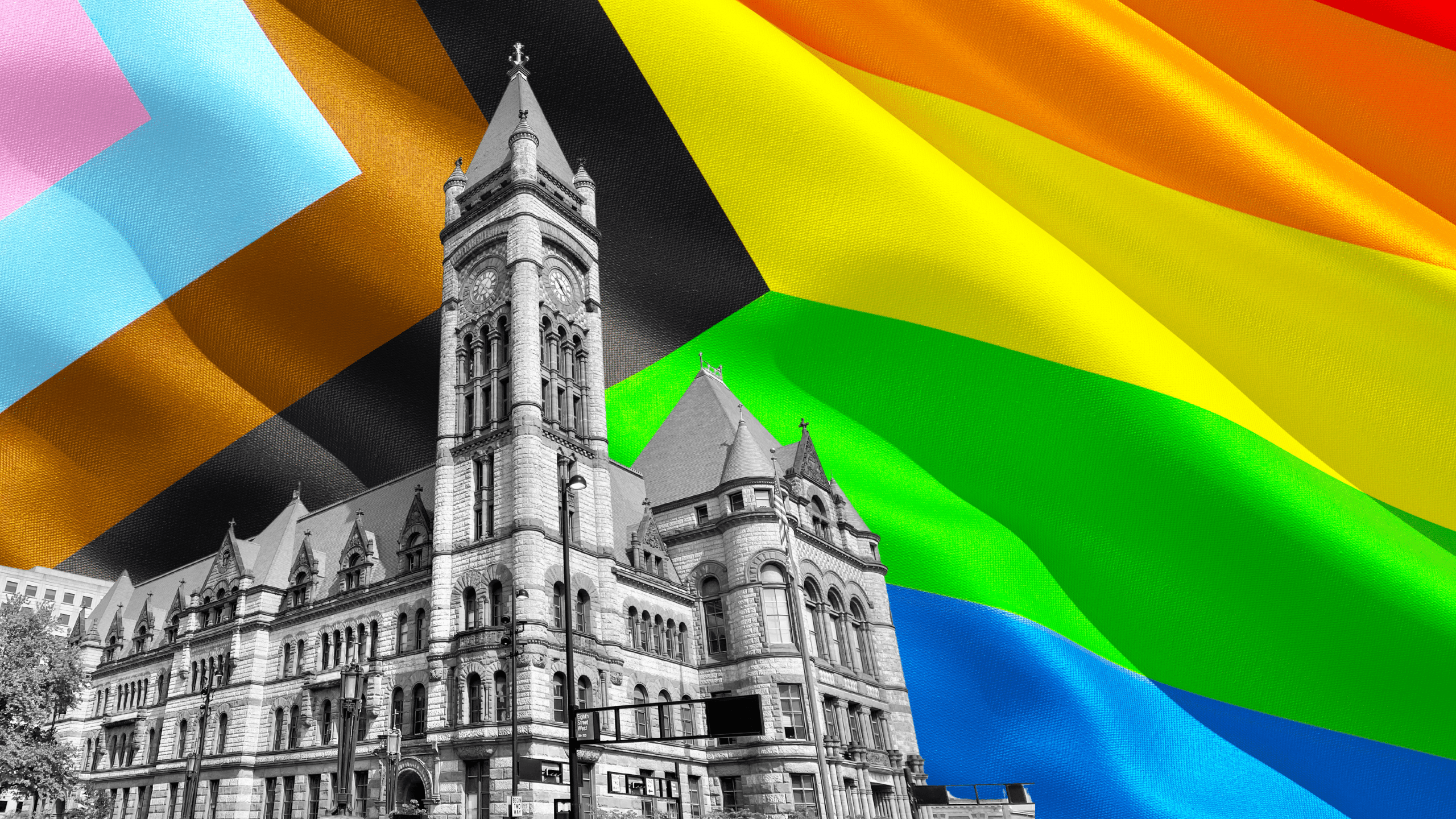 Cincinnati City Hall building is superimposed in black-and-white in front of the LGBTQ+ Progress flag.